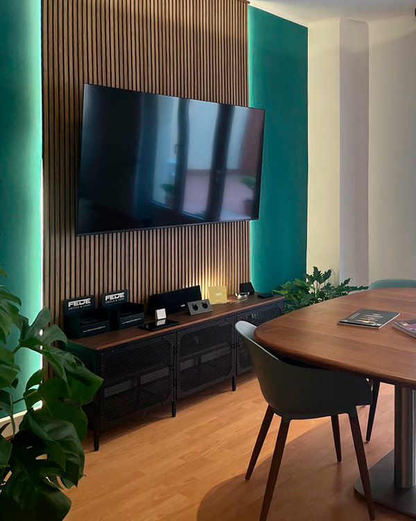Espai del showroom amb televisor, equip d’àudio i taula de reunió